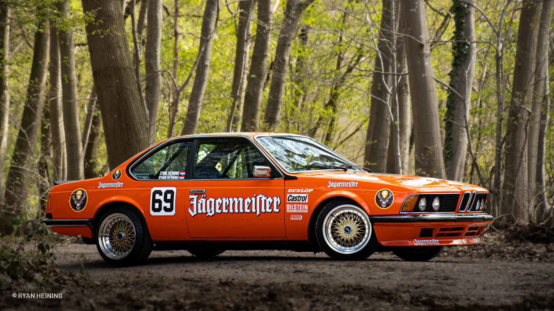 Oranje klassieke BMW in een bosrijke omgeving